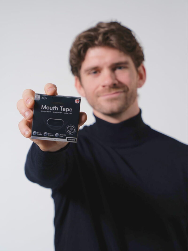 Mann hält eine Box Mouth Tape für bessere Atmung, weniger Schnarchen und besseren Schlaf