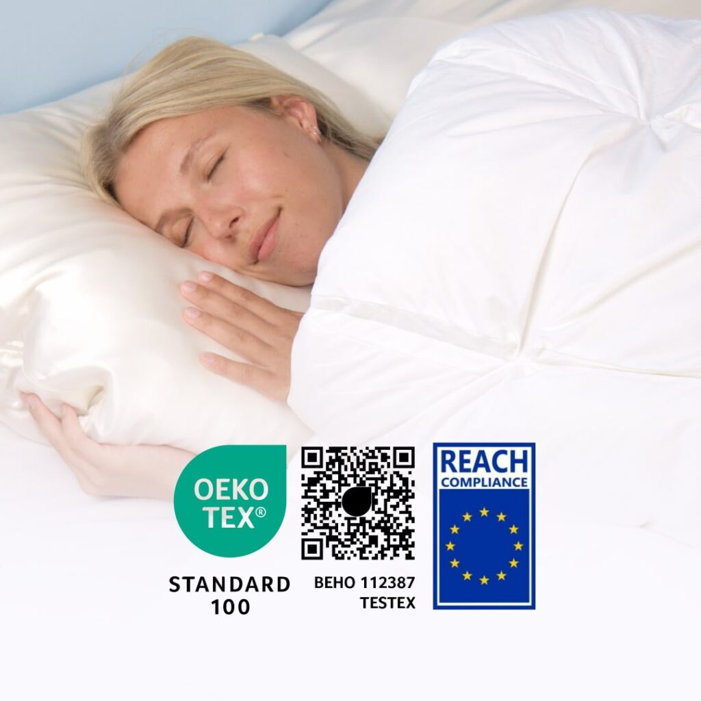 Schlafende Frau unter weißer Daunendecke, OEKO‑TEX Standard 100 und REACH‑Konformitätslogos sichtbar